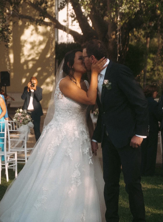 Una coppia sta accanto a una splendida torta nuziale, circondata da fiori, mentre i fuochi d'artificio illuminano il cielo notturno.